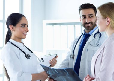 Bayan bir doktor başka bir doktora ofisinde röntgen gösteriyor.