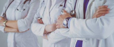 Başarılı bir tıp ekibi hastanede ayakta dururken kameraya bakıp gülümsüyor.