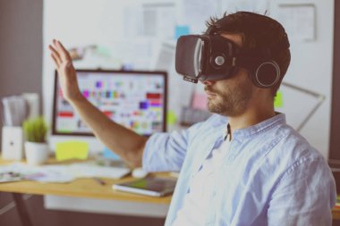 Genç erkek yazılım programcısı ofiste üç boyutlu sanal gerçeklik gözlükleriyle yeni bir uygulama test ediyor..