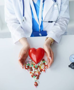 Masada kırmızı kalbi ve steteskopu olan kardiyolog.