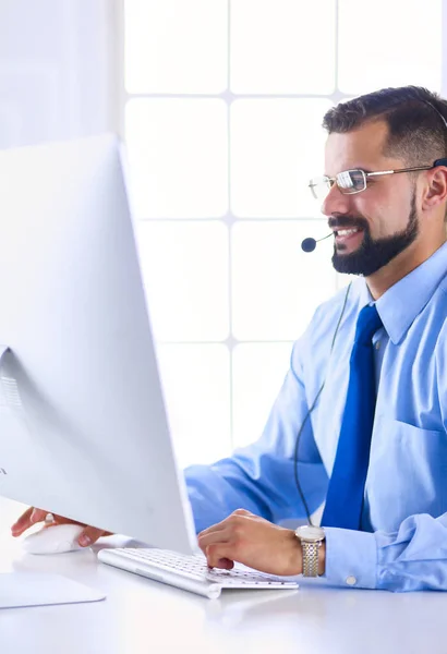 Gelukkige zakenman met headset aan het bureau in modern kantoor — Stockfoto