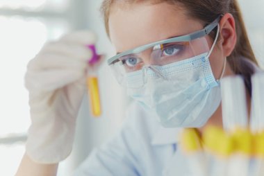 Modern laboratuvar veya hastanede plastik tıbbi tüplerle çalışan araştırmacı, doktor, bilim adamı veya laboratuvar asistanı