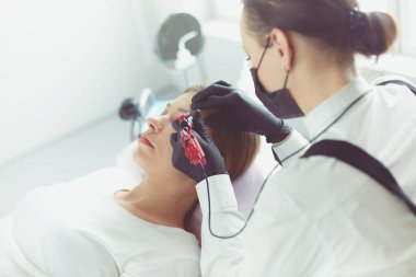 Güzellik salonunda kaş makyajı yapılan genç bir kadın.