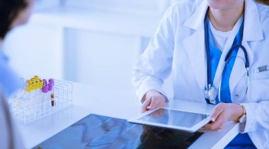 Kadın doktor hastane lobisinde tablet bilgisayar kullanarak, gülümseyerek