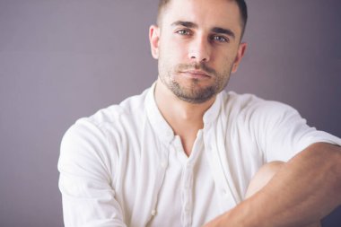 Gri arka planda yalnız oturan genç iş adamı.