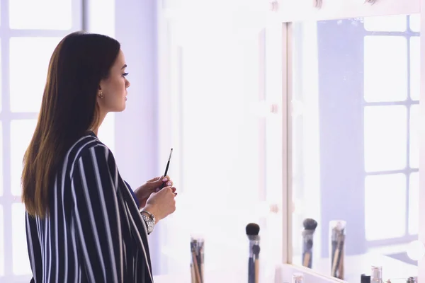 Молода жінка наносить помаду перед дзеркалом — стокове фото