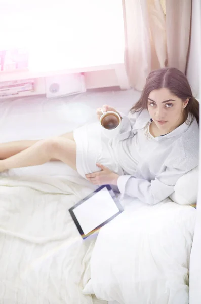 早上坐在床上用石碑和咖啡的女人的画像 — 图库照片