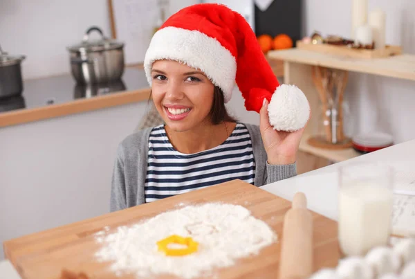 Kvinna i tomte hatt gör julkakor i köket — Stockfoto