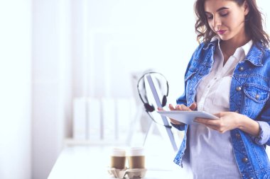 Gülümseyen kadın kahve içiyor ve kafede tablet kullanıyor.