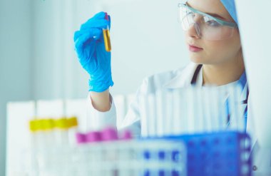 Bir kadın tıbbi veya bilimsel araştırmacı ya da kadın doktor laboratuarda bir test tüpü dolusu temiz çözeltiye bakıyor.