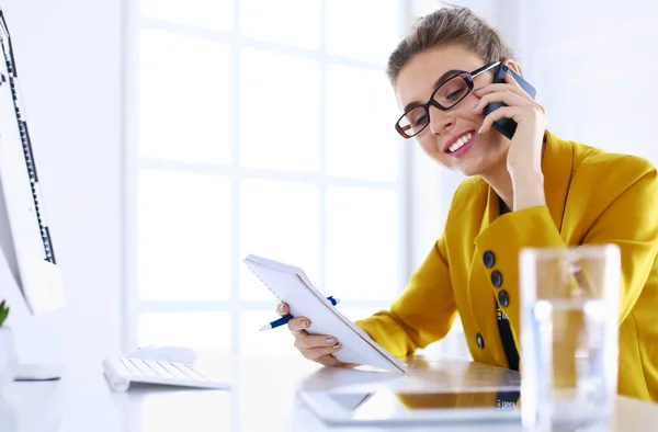 Portrait of beautiful woman making call while sitting at her workplace in front of laptop and working on new project — Stock Photo, Image