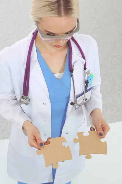 Woman doctor holding two connecting puzzle pieces — Stock Photo, Image