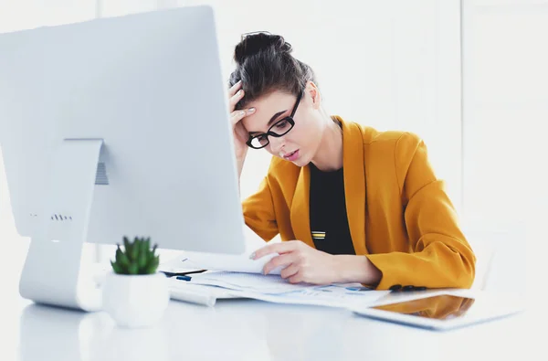 Mujer atractiva sentada en el escritorio en la oficina, trabajando con computadora portátil, sosteniendo el documento —  Fotos de Stock