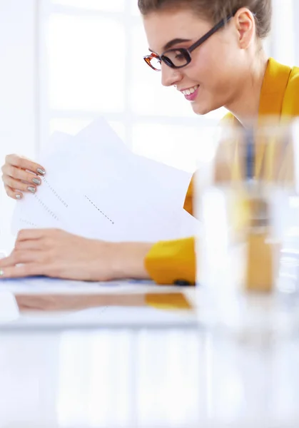 Attraktive Frau sitzt am Schreibtisch im Büro, arbeitet mit Laptop-Computer, hält Dokument — Stockfoto