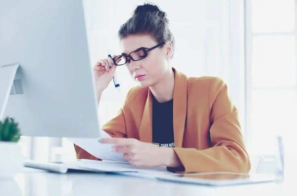 Porträtt av en ung trött affärskvinna med hjälp av laptop och arbets Stockbild