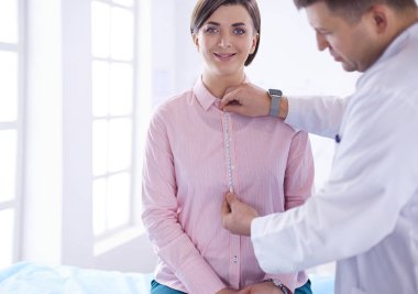 Hastanedeki genç hastaya göğsünü gösteren bir doktor.