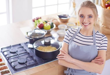 Mutfakta masanın yanında duran genç bir kadın.