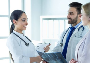 Bayan bir doktor başka bir doktora ofisinde röntgen gösteriyor.