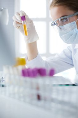 Kadın araştırmacı, beyaz şişeler ve şişelerle çevrili.