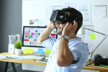 Genç erkek yazılım programcısı ofiste üç boyutlu sanal gerçeklik gözlükleriyle yeni bir uygulama test ediyor..