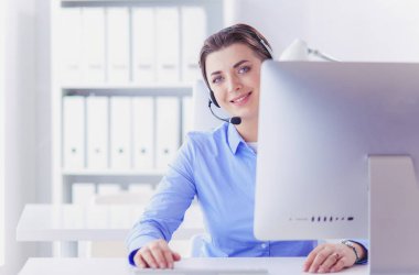 Ofisinde kulaklık takmış, telefon operatörü olarak çalışan ciddi ve güzel bir genç kadın.