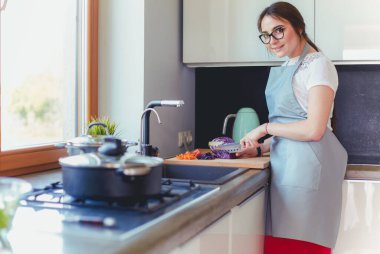 Masanın yanında duran mutfakta sebze doğrayan genç bir kadın.