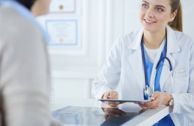 Kadın doktor hastane lobisinde tablet bilgisayar kullanarak, gülümseyerek
