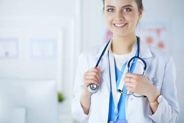 Retrato de una joven doctora con una bata blanca de pie en el hospital — Foto de Stock