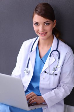 Gri arka planda oturan kadın doktor