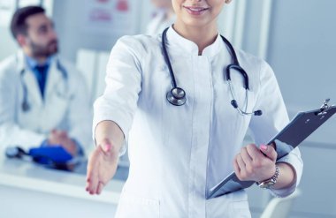 Steteskoplu kadın doktor kolları bağlı duruyor.