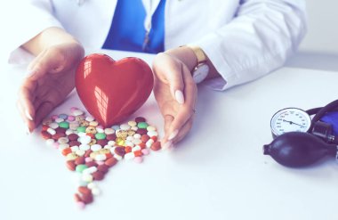 Masada kırmızı kalbi ve steteskopu olan kardiyolog.