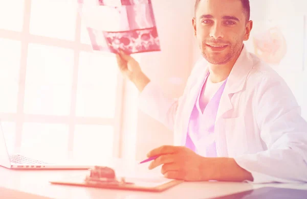 Handsome doctor is talking with young female patient and making notes while sitting in his office — Stock Photo, Image