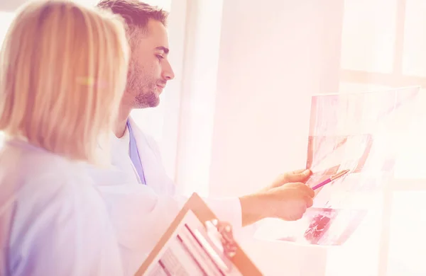 Schöner Arzt spricht mit junger Patientin und macht sich Notizen, während er in seinem Büro sitzt — Stockfoto