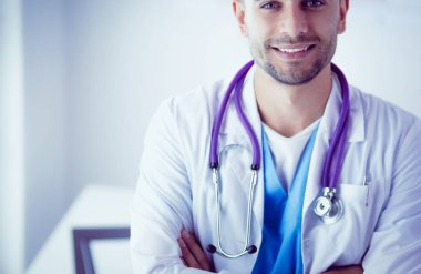 Genç ve kendinden emin erkek doktor portresi tıp ofisinde duruyor.