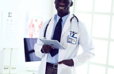 Tablet bilgisayarlı siyahi bir doktor hastanede bekliyor.