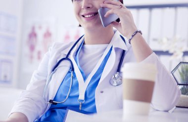Kadın doktor teşhis merkezinde telefonla konuşuyor.