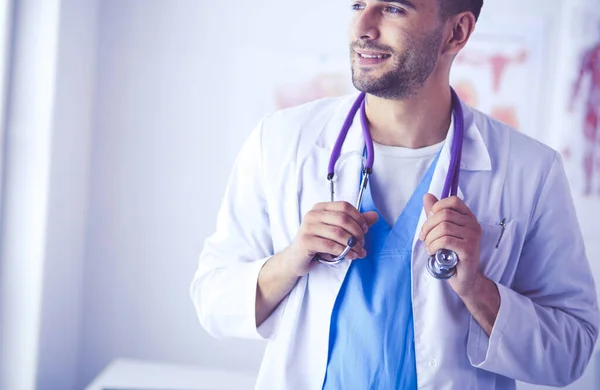 Jovem e confiante retrato médico masculino em pé no consultório médico — Fotografia de Stock