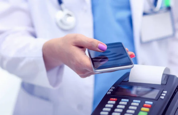 O médico está a segurar o terminal de pagamentos nas mãos. A pagar por cuidados de saúde. Doutor... — Fotografia de Stock