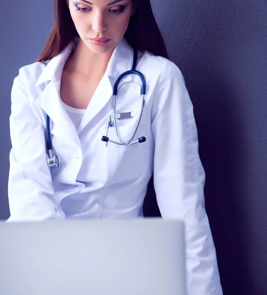 Médico femenino trabajando sentado sobre fondo gris — Foto de Stock