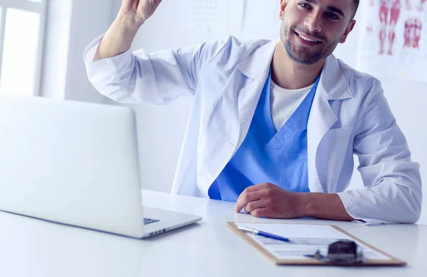 Porträt eines männlichen Arztes mit Laptop am Schreibtisch in der Arztpraxis — Stockfoto