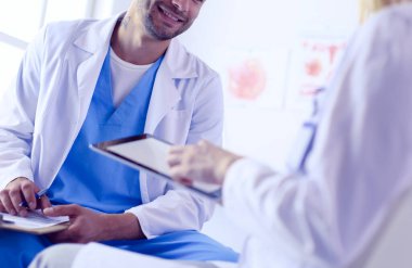 Yakışıklı doktor genç bayan doktorla konuşuyor ve ofisinde otururken notlar alıyor..