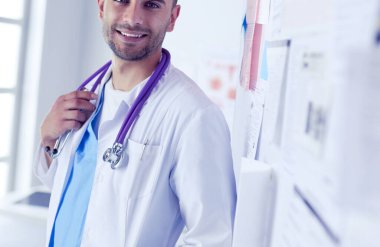 Genç ve kendinden emin erkek doktor portresi tıp ofisinde duruyor.