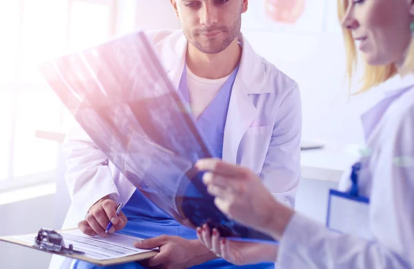 Schöner Arzt spricht mit junger Patientin und macht sich Notizen, während er in seinem Büro sitzt — Stockfoto