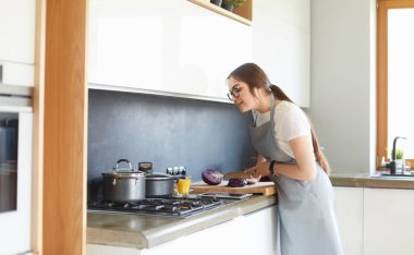 Mutfakta yemek yapmak için tablet bilgisayar kullanan genç bir kadın.