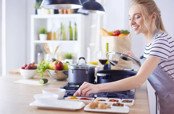 Schöne junge Frau kocht zu Hause in der Küche — Stockfoto