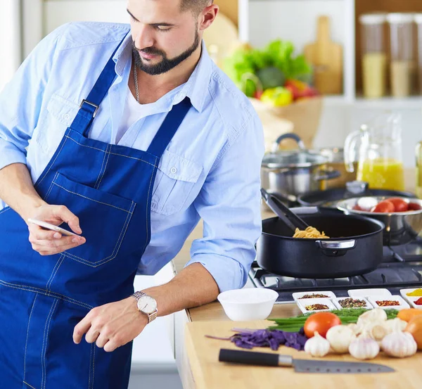 Mann hält Papiertüte voller Lebensmittel auf dem Küchenhintergrund. Shopping und gesundes Ernährungskonzept — Stockfoto