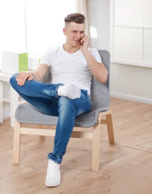 Evdeki koltukta oturan yakışıklı, kendine güvenen adam.