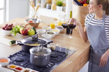 Güzel kadın mutfakta şarap içiyor.