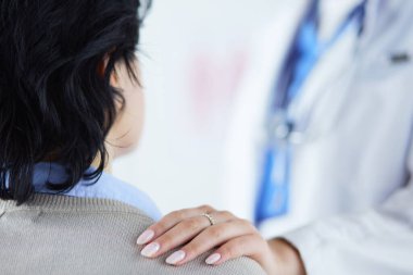 Gülümseyen doktor kadın hastanede bir hastayla konuşuyor.