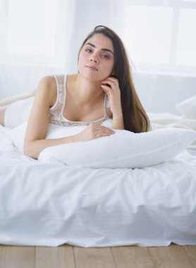 Güzel bir kadın yatağında uzanıyor.